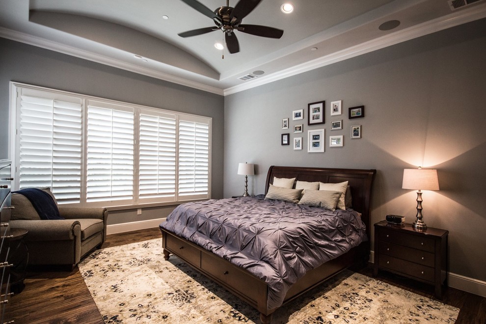 This is an example of a large transitional master bedroom in Dallas with grey walls, dark hardwood floors, no fireplace and brown floor.