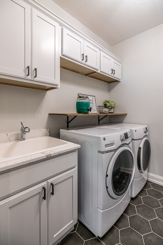 This is an example of a large arts and crafts single-wall dedicated laundry room in Other with a single-bowl sink, shaker cabinets, white cabinets, quartzite benchtops, grey walls, ceramic floors, a side-by-side washer and dryer, black floor and white benchtop.