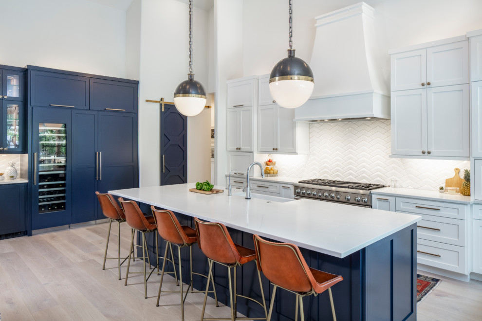 Inspiration for a large transitional u-shaped light wood floor and beige floor eat-in kitchen remodel in Austin with a farmhouse sink, white backsplash, an island, white countertops, quartzite countertops, ceramic backsplash, recessed-panel cabinets, white cabinets and paneled appliances