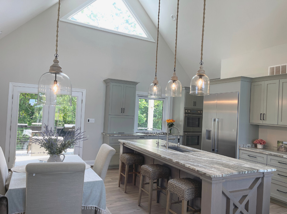 This is an example of a rural l-shaped open plan kitchen in Other with a submerged sink, recessed-panel cabinets, grey cabinets, granite worktops, stainless steel appliances, medium hardwood flooring, an island, brown floors, grey worktops and a vaulted ceiling.