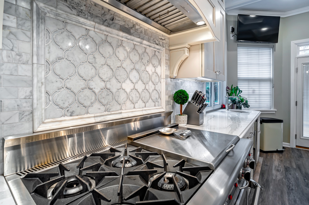 Inspiration for a large transitional single-wall medium tone wood floor and brown floor eat-in kitchen remodel in Philadelphia with a farmhouse sink, shaker cabinets, white cabinets, quartz countertops, gray backsplash, porcelain backsplash, stainless steel appliances, an island and white countertops