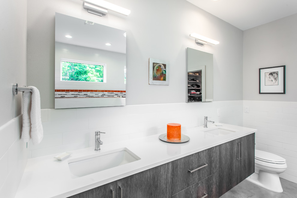 Inspiration for a mid-sized contemporary master bathroom in New Orleans with flat-panel cabinets, dark wood cabinets, a drop-in tub, an open shower, a one-piece toilet, white tile, ceramic tile, red walls, concrete floors, an undermount sink, engineered quartz benchtops, grey floor, an open shower and white benchtops.