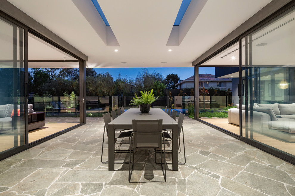 Contemporary patio in Melbourne with natural stone pavers and a roof extension.