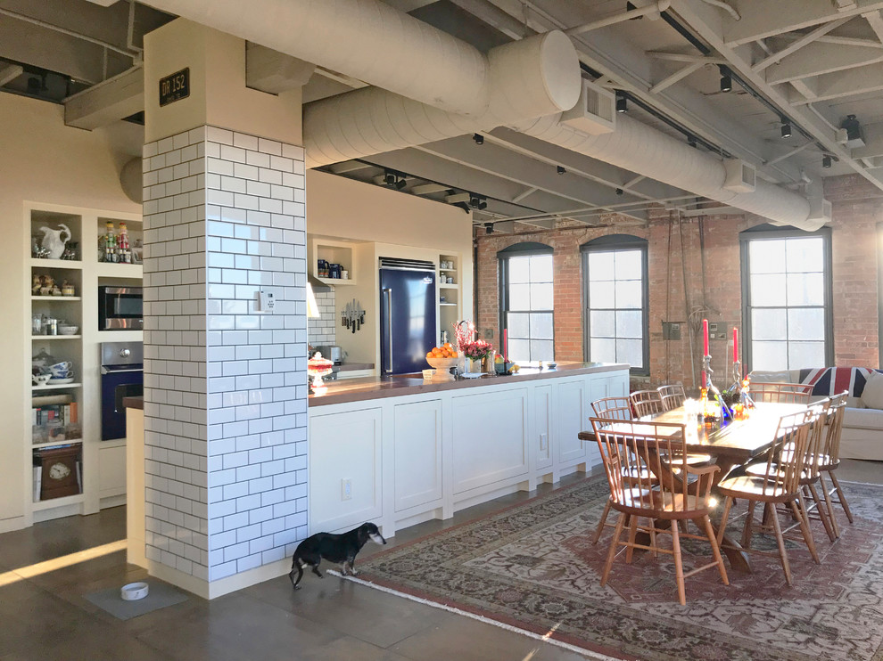 This is an example of an industrial galley open plan kitchen in Cleveland with open cabinets, white cabinets, coloured appliances, concrete floors, with island, grey floor and brown benchtop.