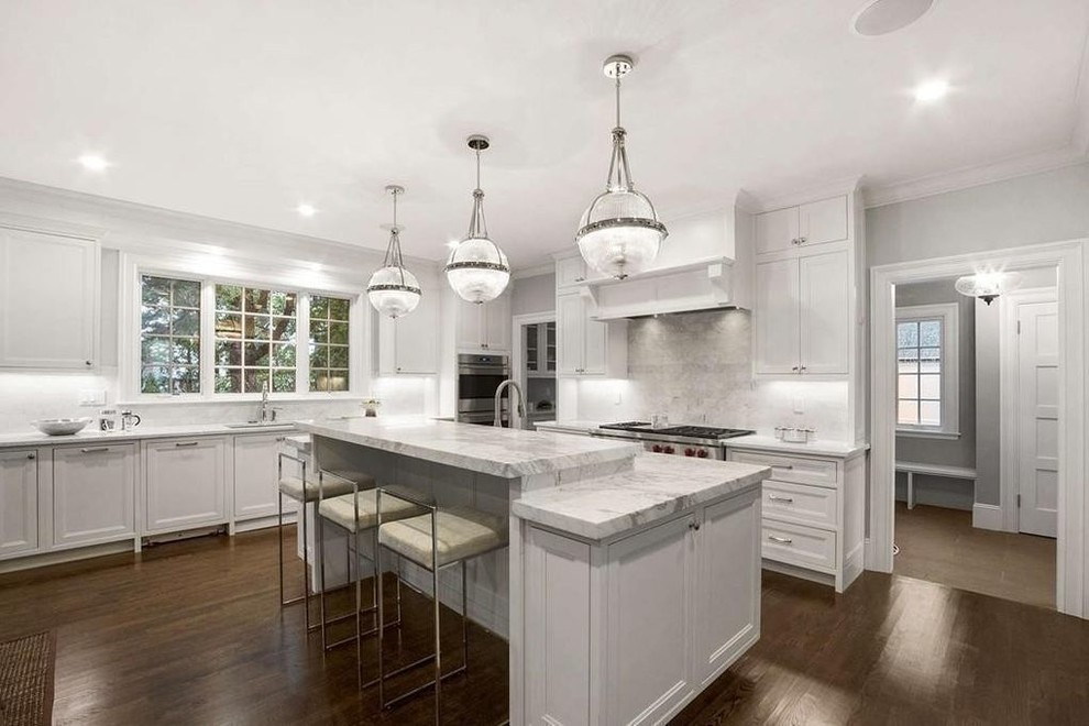 This is an example of an expansive traditional l-shaped eat-in kitchen in Boston with an undermount sink, beaded inset cabinets, white cabinets, marble benchtops, grey splashback, marble splashback, stainless steel appliances, dark hardwood floors, with island, brown floor and white benchtop.