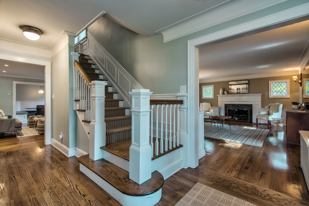 Large transitional wood l-shaped staircase in New York with wood risers, wood railing and decorative wall panelling.