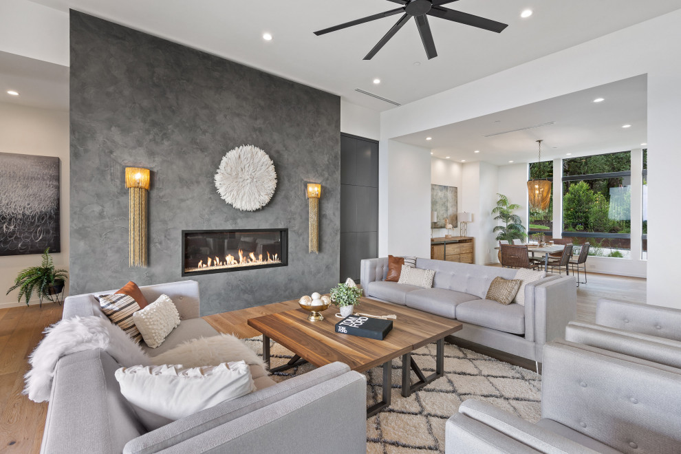 Photo of a mid-sized contemporary formal open concept living room in Austin with white walls, medium hardwood floors, a standard fireplace, a metal fireplace surround and no tv.