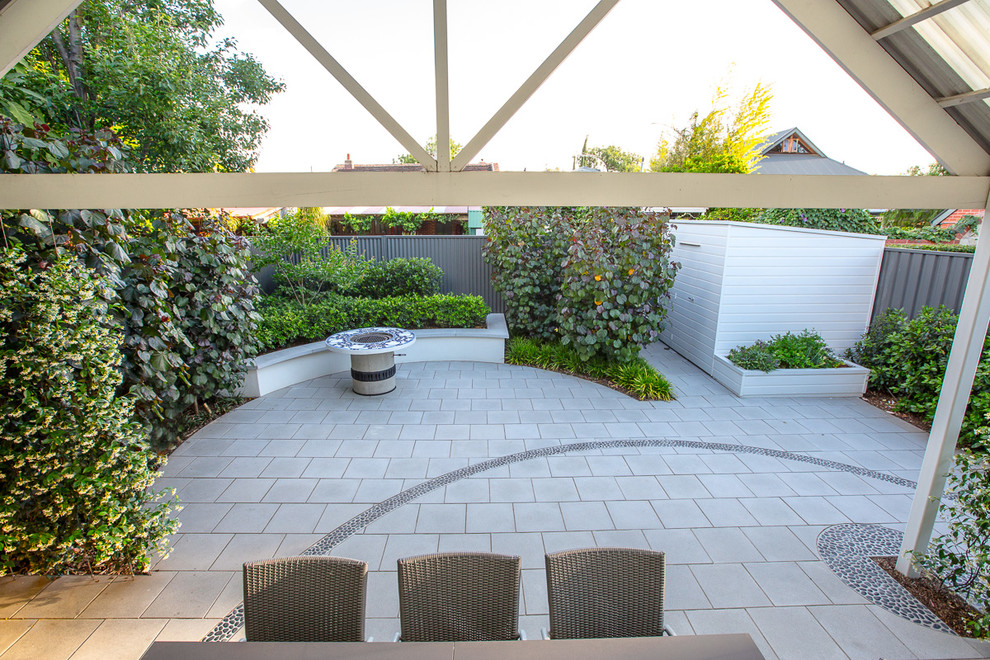 This is an example of a transitional backyard patio in Melbourne with concrete pavers and a pergola.