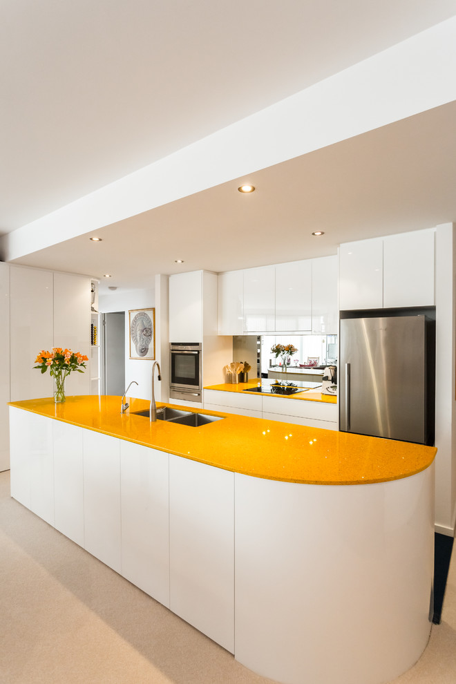 Small contemporary galley open plan kitchen in Perth with an undermount sink, flat-panel cabinets, white cabinets, quartz benchtops, glass sheet splashback, stainless steel appliances and yellow benchtop.