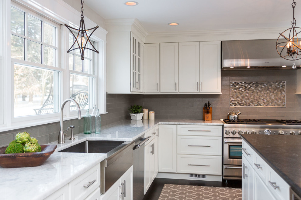 Large transitional l-shaped dark wood floor and brown floor eat-in kitchen photo in Boston with a farmhouse sink, recessed-panel cabinets, white cabinets, marble countertops, ceramic backsplash, stainless steel appliances, gray backsplash, an island and white countertops