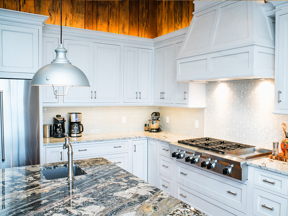 Example of a large transitional u-shaped medium tone wood floor and brown floor eat-in kitchen design with white cabinets, granite countertops, white backsplash, ceramic backsplash, stainless steel appliances, an island, an undermount sink and shaker cabinets