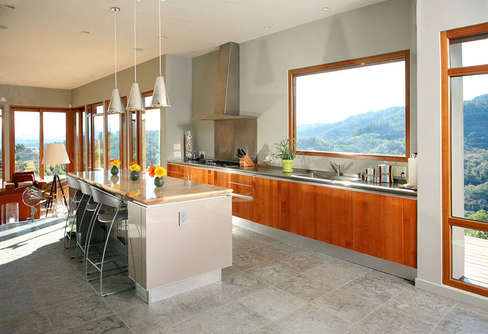 Photo of a mid-sized contemporary single-wall open plan kitchen in San Francisco with flat-panel cabinets, with island, an integrated sink, medium wood cabinets, stainless steel benchtops, metallic splashback, metal splashback, stainless steel appliances, slate floors and grey floor.