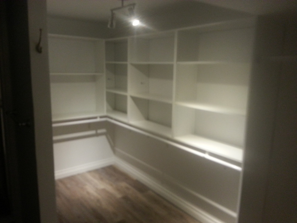 This is an example of a large transitional storage and wardrobe in Calgary with open cabinets, vinyl floors and brown floor.