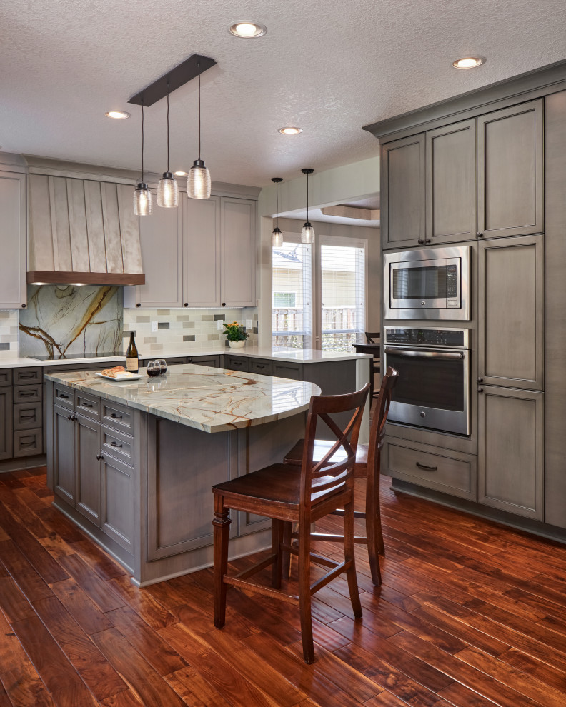 Example of a mid-sized transitional l-shaped dark wood floor and brown floor enclosed kitchen design in Portland with an undermount sink, recessed-panel cabinets, gray cabinets, granite countertops, multicolored backsplash, stainless steel appliances, an island and multicolored countertops