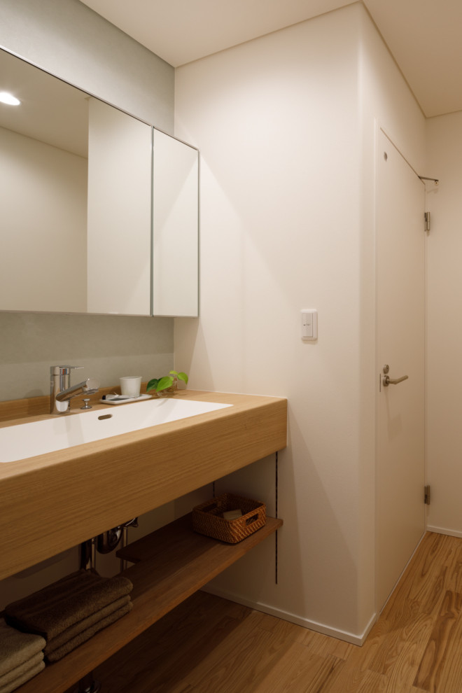 Inspiration för ett nordiskt vit vitt toalett, med öppna hyllor, skåp i ljust trä, vita väggar, plywoodgolv, ett undermonterad handfat och laminatbänkskiva