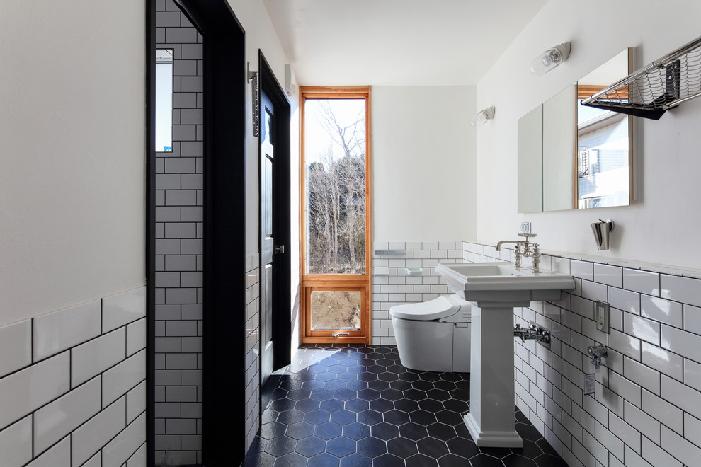 Design ideas for a traditional powder room in Tokyo with white walls, black floor, a pedestal sink and a one-piece toilet.