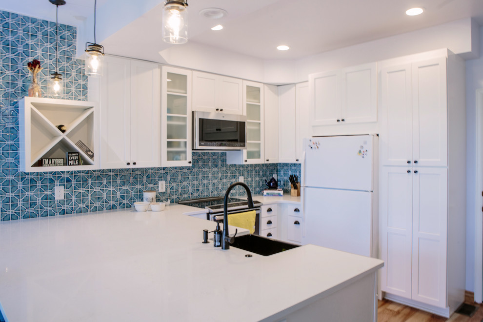 Inspiration for a small eclectic u-shaped eat-in kitchen in Denver with a farmhouse sink, shaker cabinets, white cabinets, quartz benchtops, blue splashback, ceramic splashback, stainless steel appliances, light hardwood floors, a peninsula and brown floor.