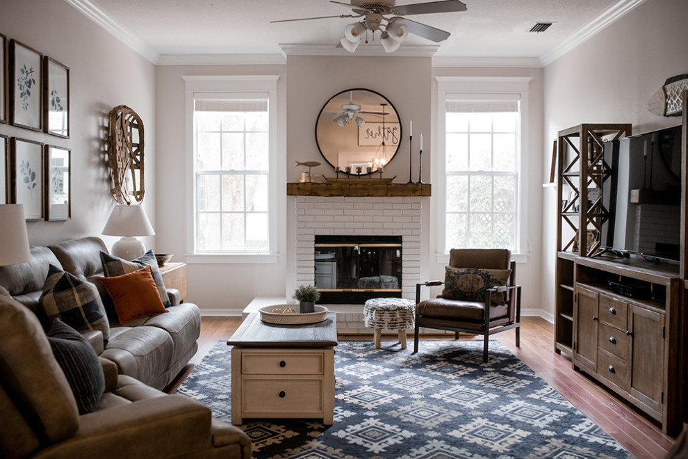 Design ideas for a large country open concept family room in Tampa with grey walls, laminate floors, a standard fireplace, a brick fireplace surround, a freestanding tv and brown floor.