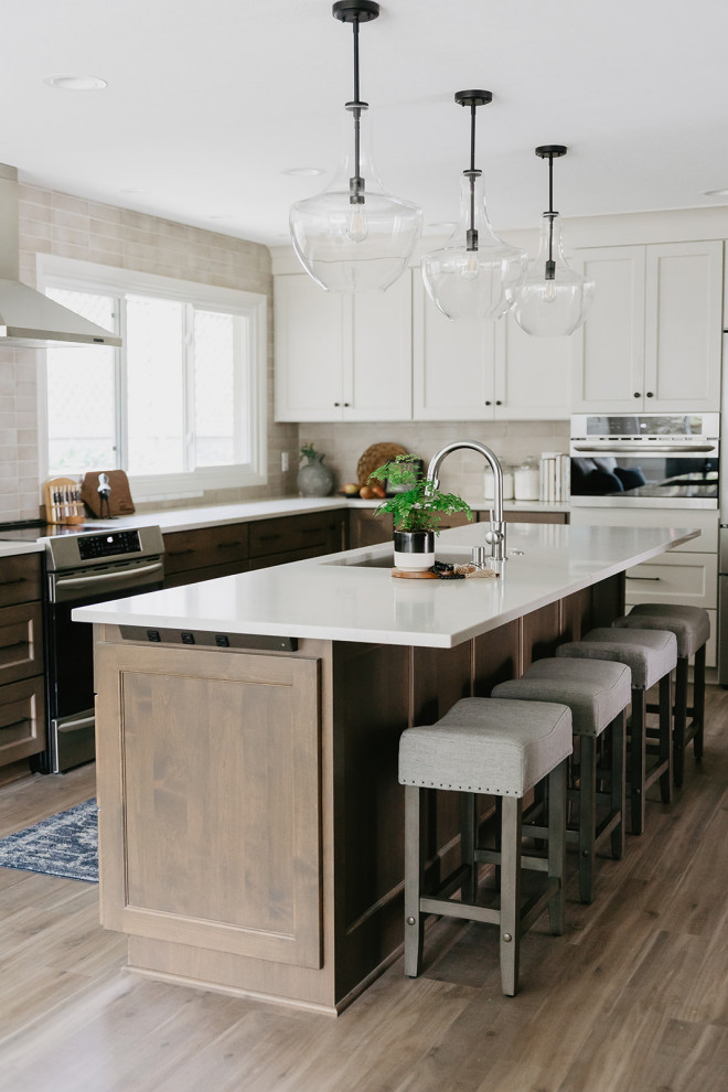Mid-sized transitional l-shaped vinyl floor and brown floor eat-in kitchen photo with an undermount sink, shaker cabinets, medium tone wood cabinets, quartz countertops, beige backsplash, porcelain backsplash, stainless steel appliances, an island and white countertops