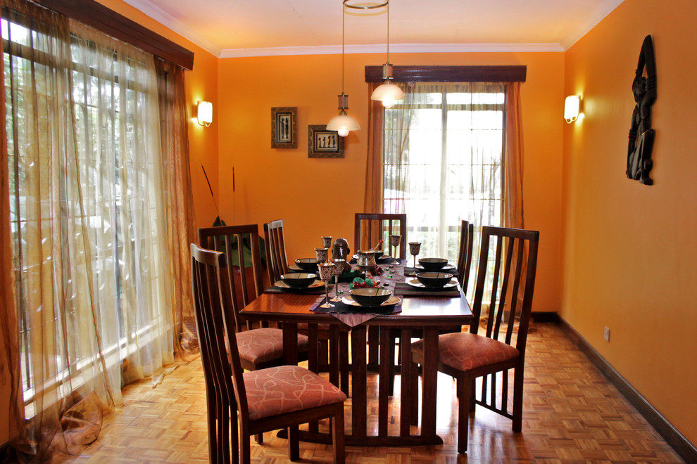 Mittelgroße Rustikale Wohnküche mit oranger Wandfarbe, gebeiztem Holzboden, Eckkamin und Kaminumrandung aus Backstein in Sonstige