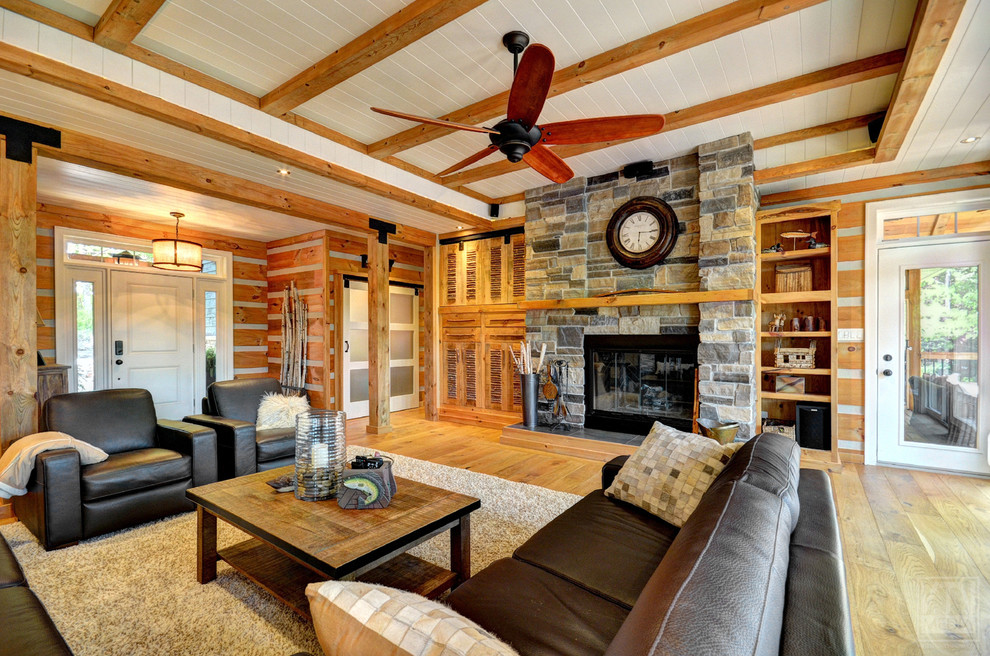 Photo of a large country open concept living room in Toronto with light hardwood floors, a standard fireplace, a stone fireplace surround and a concealed tv.