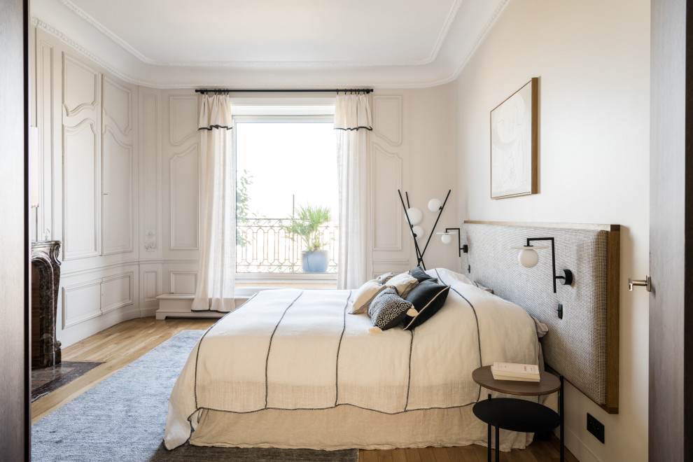 Inspiration för moderna sovrum, med beige väggar, mellanmörkt trägolv, en standard öppen spis och brunt golv