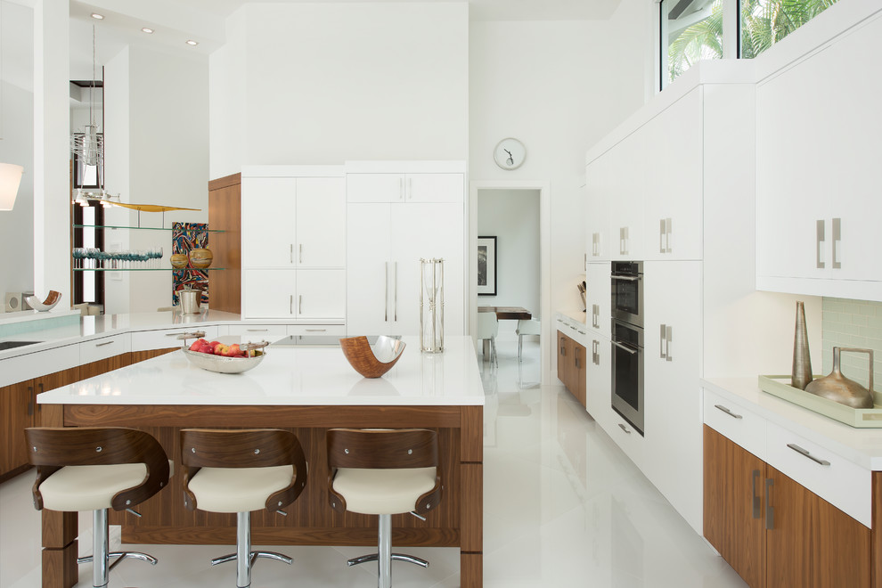 Example of a large transitional u-shaped porcelain tile and white floor kitchen design with an undermount sink, flat-panel cabinets, light wood cabinets, quartzite countertops, blue backsplash, glass tile backsplash, stainless steel appliances, an island and white countertops