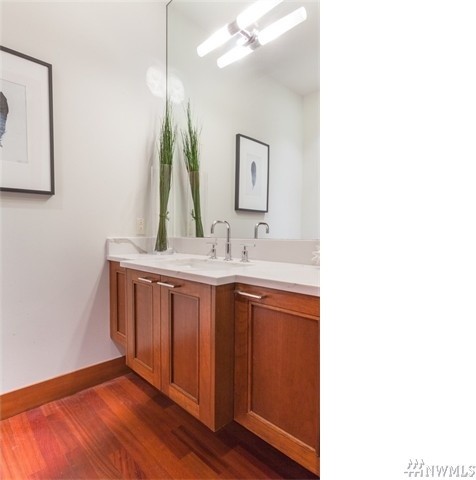 This is an example of a mid-sized 3/4 bathroom in Seattle with brown cabinets, white walls, light hardwood floors, an undermount sink and engineered quartz benchtops.