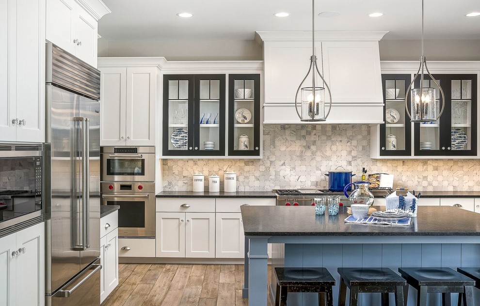 Inspiration for a mid-sized beach style l-shaped eat-in kitchen in Chicago with shaker cabinets, white cabinets, soapstone benchtops, grey splashback, marble splashback, stainless steel appliances, dark hardwood floors, with island and beige floor.