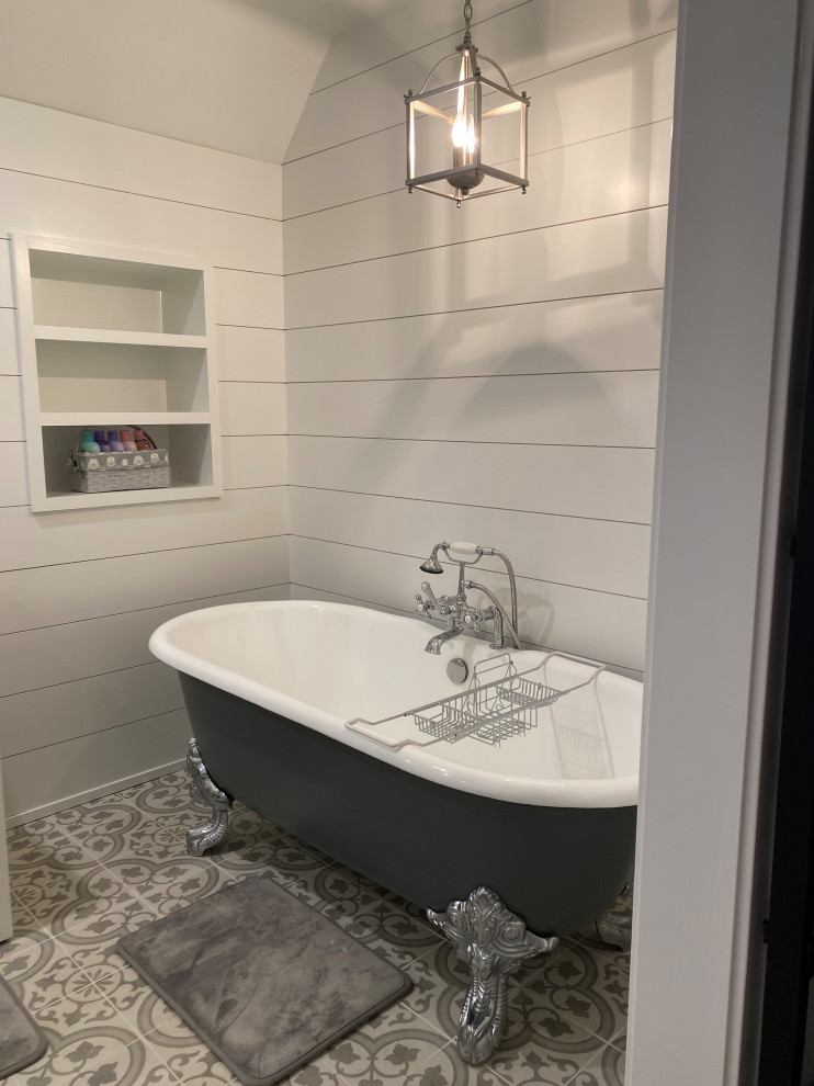 Photo of a large transitional master bathroom in Nashville with recessed-panel cabinets, white cabinets, a claw-foot tub, a double shower, an urinal, white walls, porcelain floors, an undermount sink, marble benchtops, a hinged shower door, grey benchtops, an enclosed toilet, a double vanity, a freestanding vanity, vaulted and planked wall panelling.
