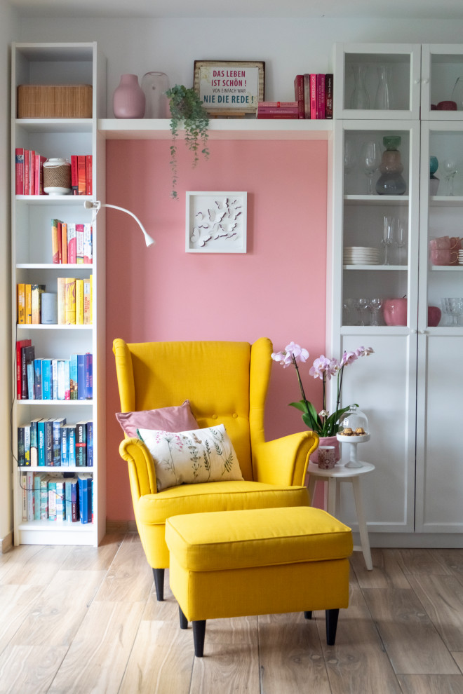 Пример оригинального дизайна: маленькая открытая гостиная комната в скандинавском стиле с с книжными шкафами и полками, розовыми стенами и коричневым полом для на участке и в саду