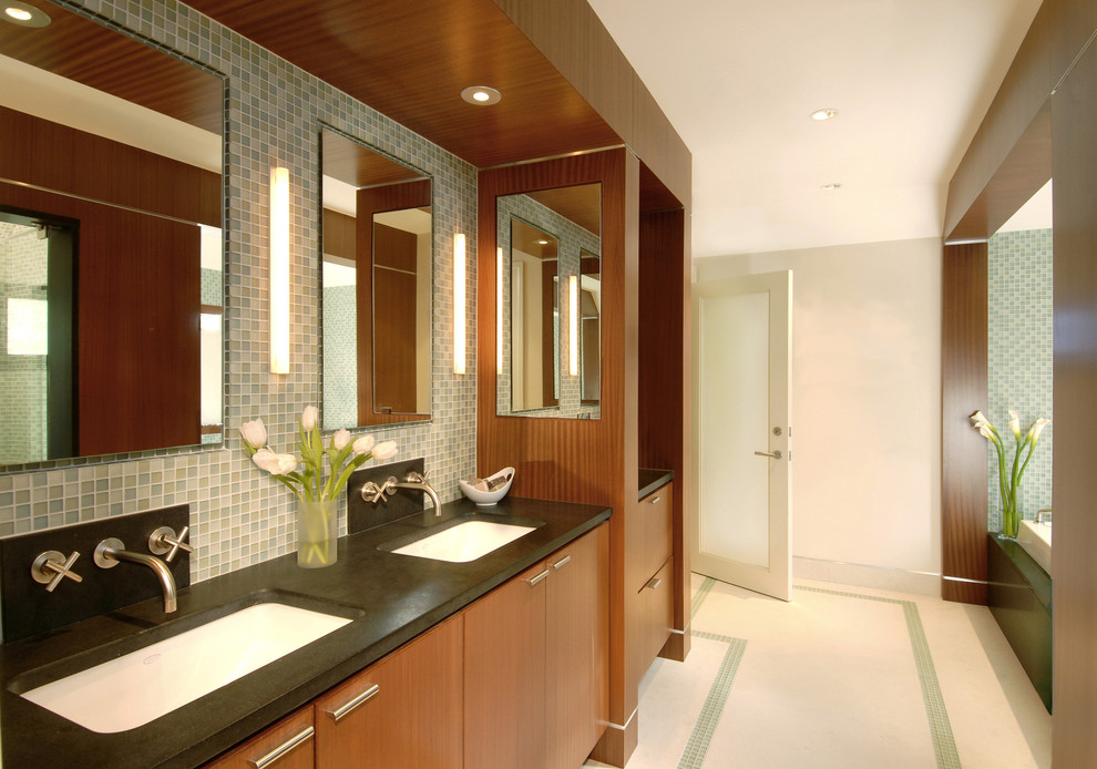 This is an example of a large contemporary master bathroom in Boston with flat-panel cabinets, medium wood cabinets, a drop-in tub, a double shower, blue tile, mosaic tile, white walls, limestone floors, an undermount sink, white floor and a hinged shower door.