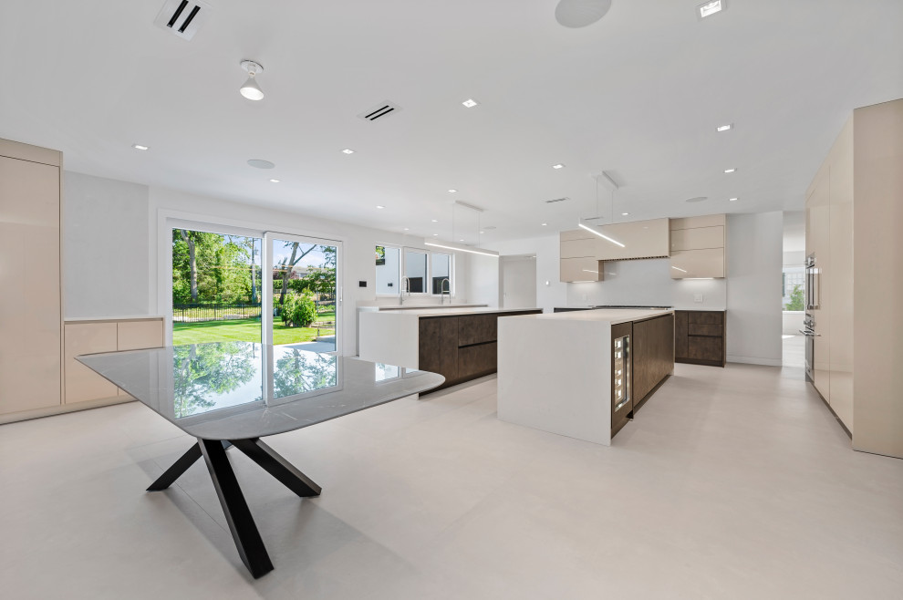 Inspiration for a large contemporary u-shaped kitchen/diner in New York with a submerged sink, flat-panel cabinets, grey cabinets, engineered stone countertops, white splashback, engineered quartz splashback, stainless steel appliances, marble flooring, multiple islands, white floors and white worktops.
