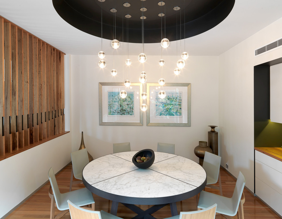 Photo of a contemporary dining room in Melbourne with white walls and medium hardwood floors.
