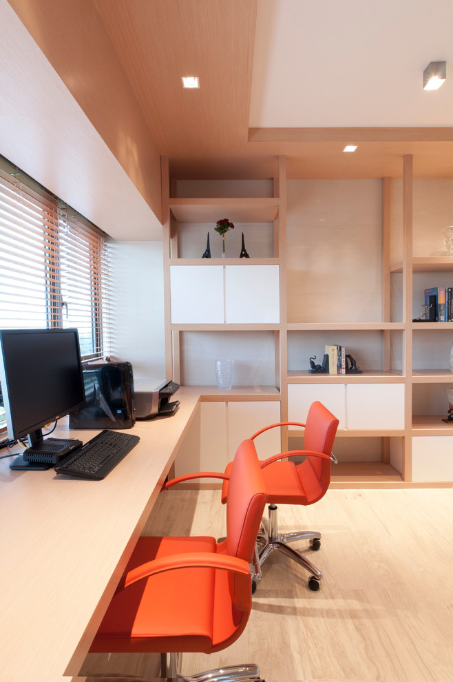 Modern home office in Singapore with light hardwood floors and a built-in desk.
