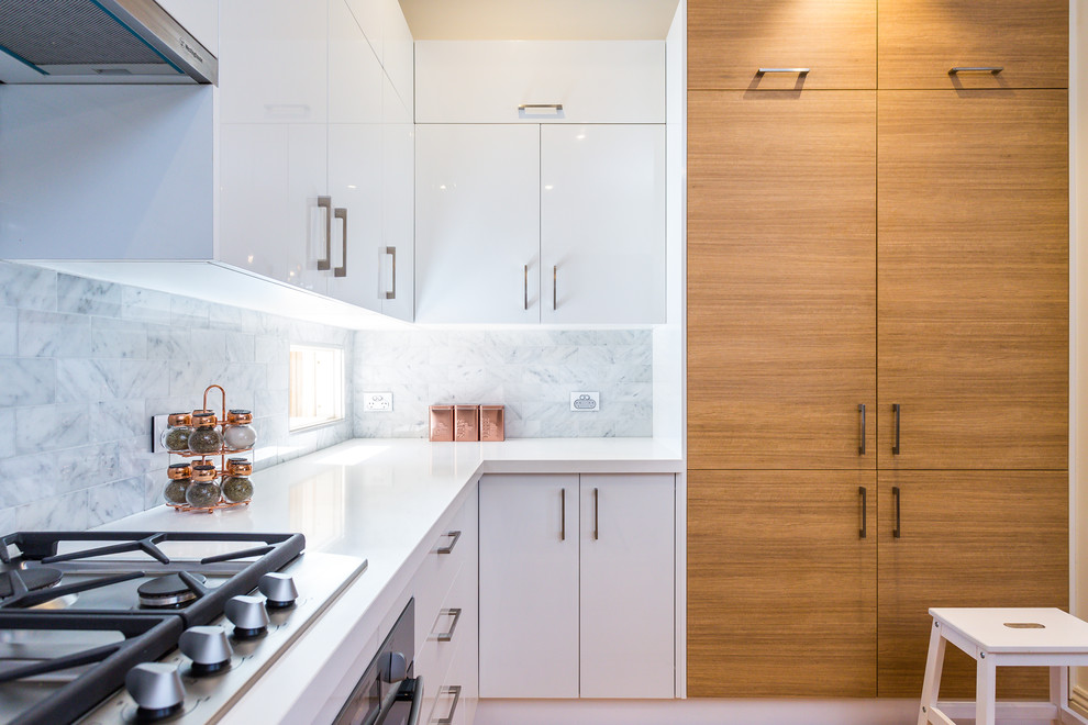 Mid-sized traditional u-shaped open plan kitchen in Melbourne with an undermount sink, open cabinets, solid surface benchtops, white splashback, stone tile splashback, stainless steel appliances, medium hardwood floors, with island and white benchtop.