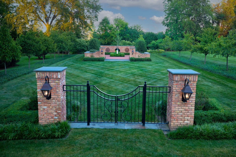 Immagine di un grande giardino formale tradizionale esposto in pieno sole davanti casa in estate con un ingresso o sentiero, pavimentazioni in pietra naturale e recinzione in pietra