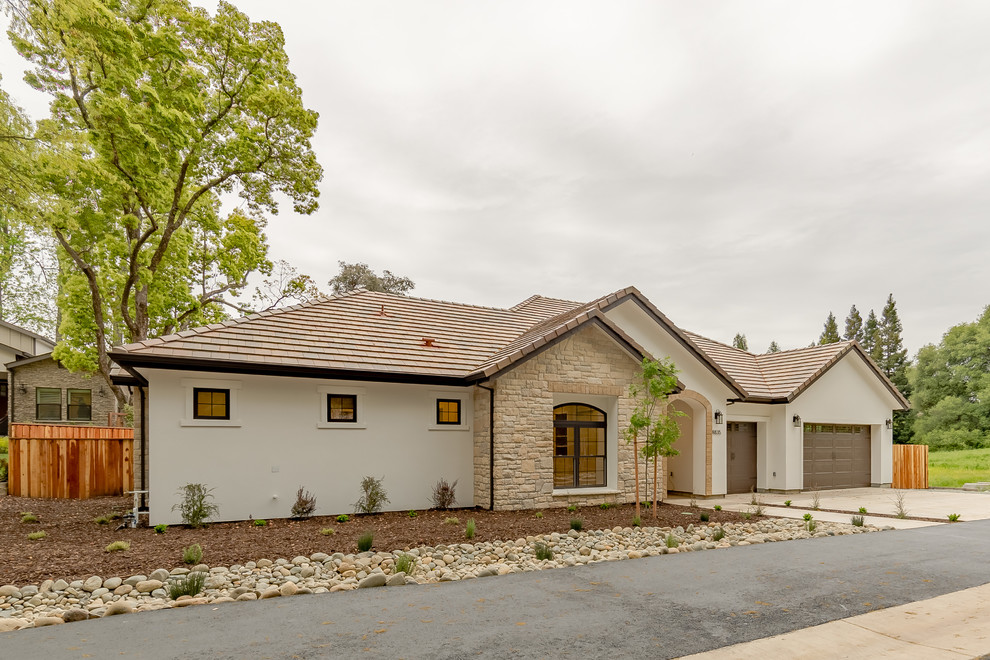 Photo of a mid-sized country one-storey stucco beige house exterior in Sacramento with a gable roof and a tile roof.