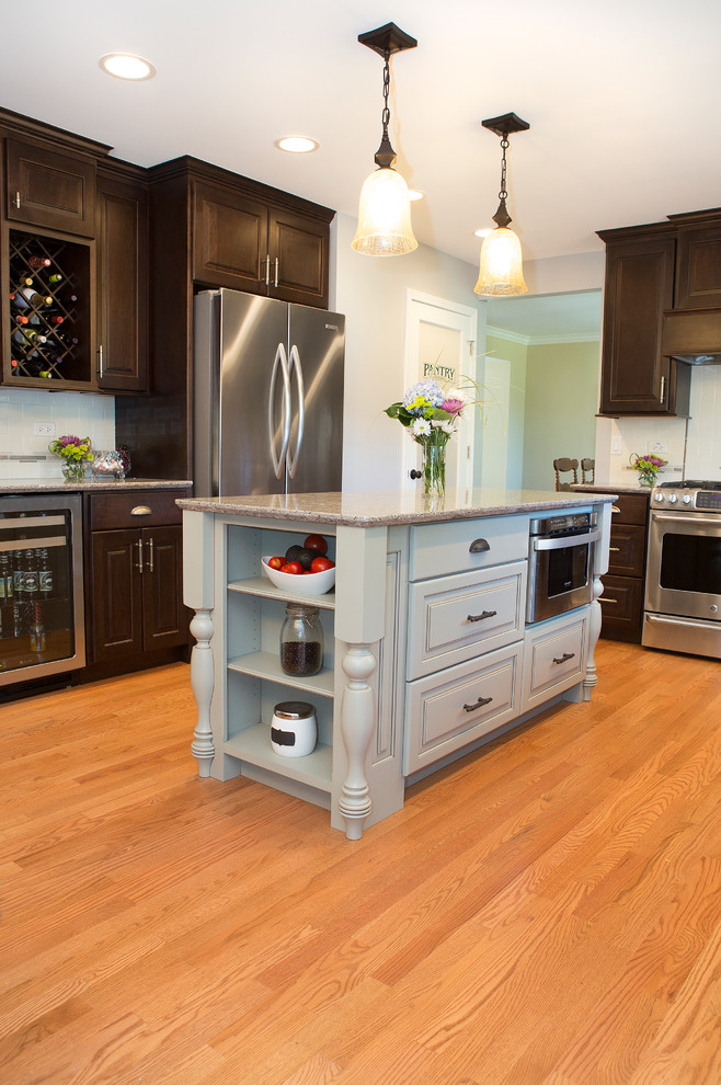 Mid-sized transitional u-shaped light wood floor enclosed kitchen photo in Chicago with an undermount sink, raised-panel cabinets, dark wood cabinets, quartz countertops, beige backsplash, ceramic backsplash, stainless steel appliances and an island