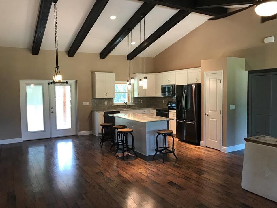 Example of a mid-sized transitional l-shaped dark wood floor and brown floor open concept kitchen design in Orlando with an undermount sink, recessed-panel cabinets, white cabinets, granite countertops, gray backsplash, subway tile backsplash, stainless steel appliances and an island