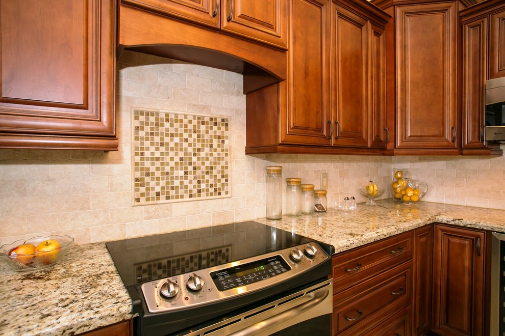 Mid-sized transitional u-shaped porcelain tile eat-in kitchen photo in Miami with an undermount sink, raised-panel cabinets, brown cabinets, granite countertops, beige backsplash, stone tile backsplash, stainless steel appliances, beige walls and a peninsula