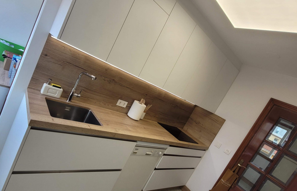 Inspiration for a mid-sized scandinavian galley separate kitchen in Other with an undermount sink, flat-panel cabinets, white cabinets, wood benchtops, beige splashback, timber splashback, stainless steel appliances, ceramic floors, no island, beige floor and beige benchtop.