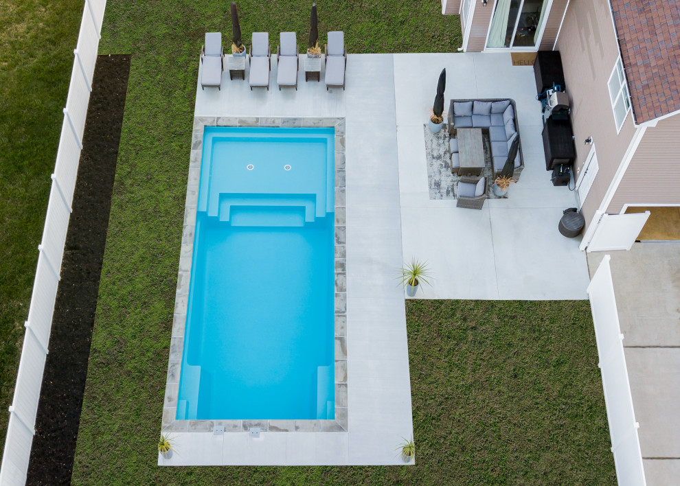 Foto de piscina alargada contemporánea grande rectangular en patio trasero con paisajismo de piscina y adoquines de ladrillo