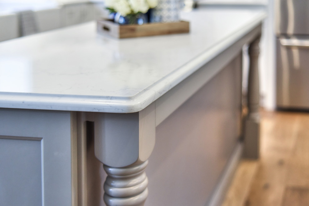 Inspiration for a large transitional l-shaped medium tone wood floor home design remodel in Jacksonville with a farmhouse sink, shaker cabinets, quartz countertops and an island