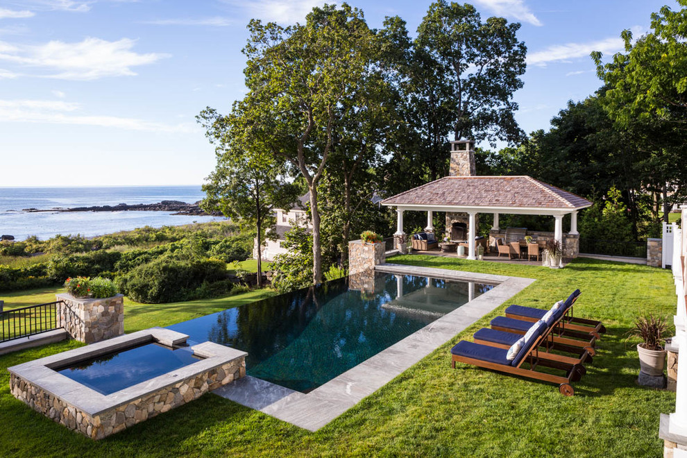 Photo of a mid-sized traditional backyard rectangular infinity pool in Portland Maine with a hot tub and natural stone pavers.
