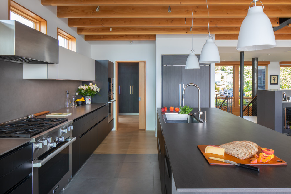 Inspiration for a mid-sized modern galley eat-in kitchen in Seattle with an undermount sink, flat-panel cabinets, dark wood cabinets, solid surface benchtops, grey splashback, porcelain splashback, panelled appliances, with island, yellow floor, grey benchtop and wood.