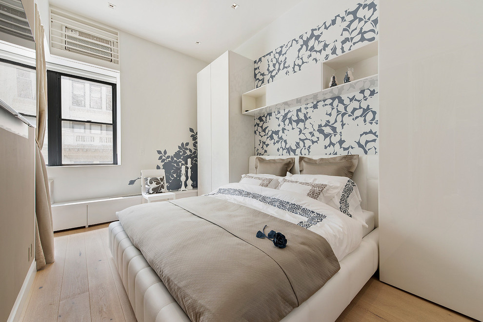Photo of a contemporary bedroom in New York with white walls and light hardwood floors.