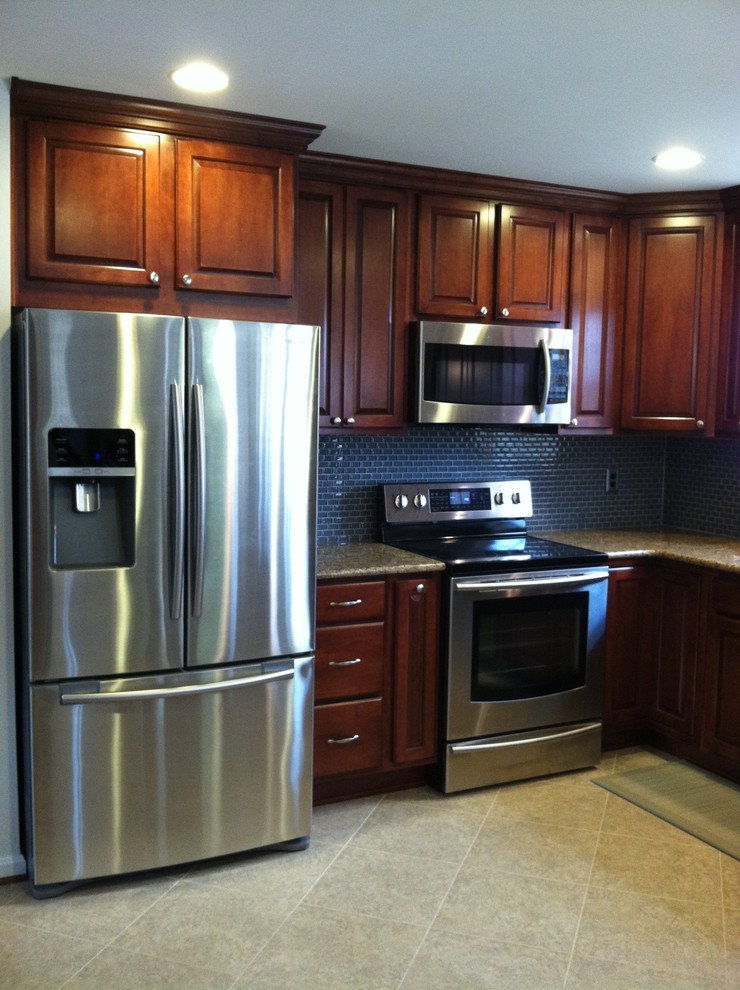 Example of a large transitional u-shaped ceramic tile and beige floor enclosed kitchen design with an undermount sink, raised-panel cabinets, dark wood cabinets, blue backsplash, ceramic backsplash, stainless steel appliances, a peninsula and granite countertops