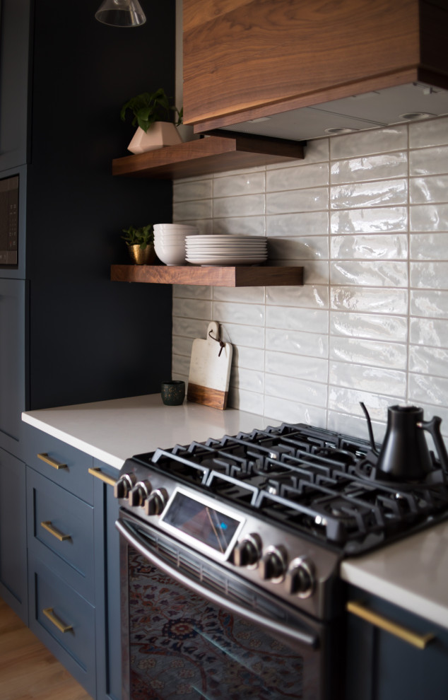 Mid-sized transitional l-shaped medium tone wood floor open concept kitchen photo in Denver with shaker cabinets, blue cabinets, granite countertops, white backsplash, ceramic backsplash, stainless steel appliances, an island and white countertops