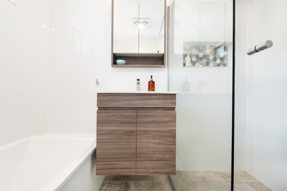 This is an example of a small contemporary bathroom in Other with medium wood cabinets, a corner tub, a corner shower, white tile, white walls, grey floor and a hinged shower door.